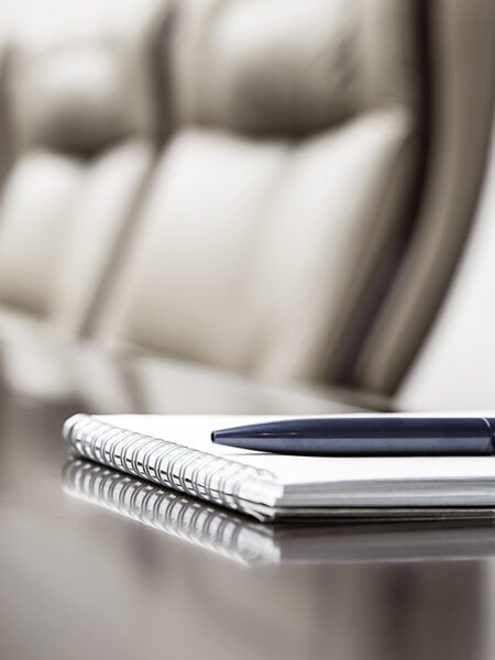 Closeup of notepad for agenda kept on table in empty corporate conference room before business meeting