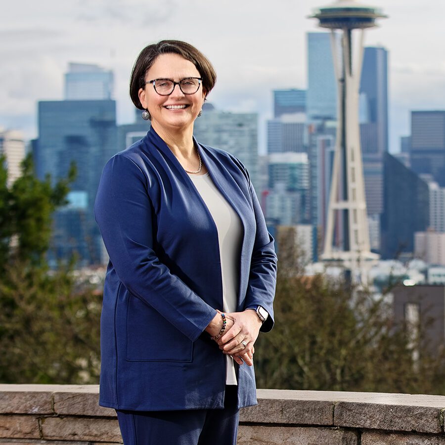 A woman smiling with the Space Needle blurred in the background