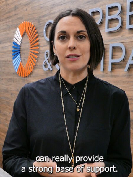 Woman standing, her elbow on a countertop, and smiling