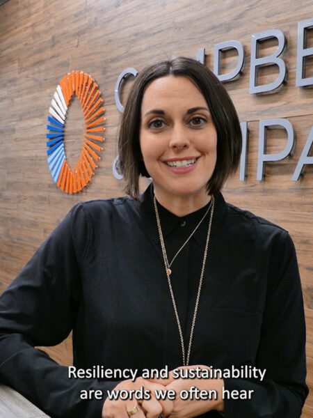 Woman standing, her elbow on a countertop, and smiling